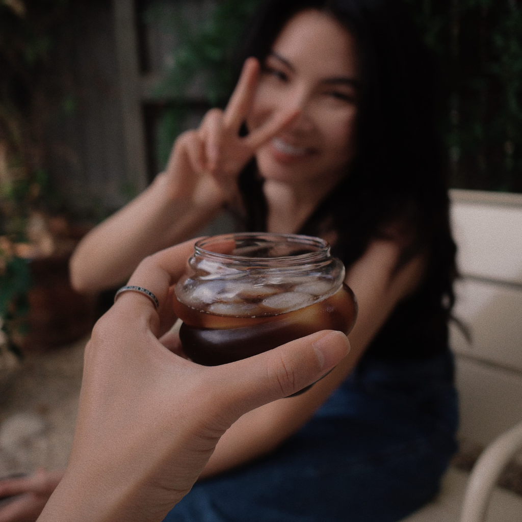 Person sitting outdoors holding a ZIPURE americano