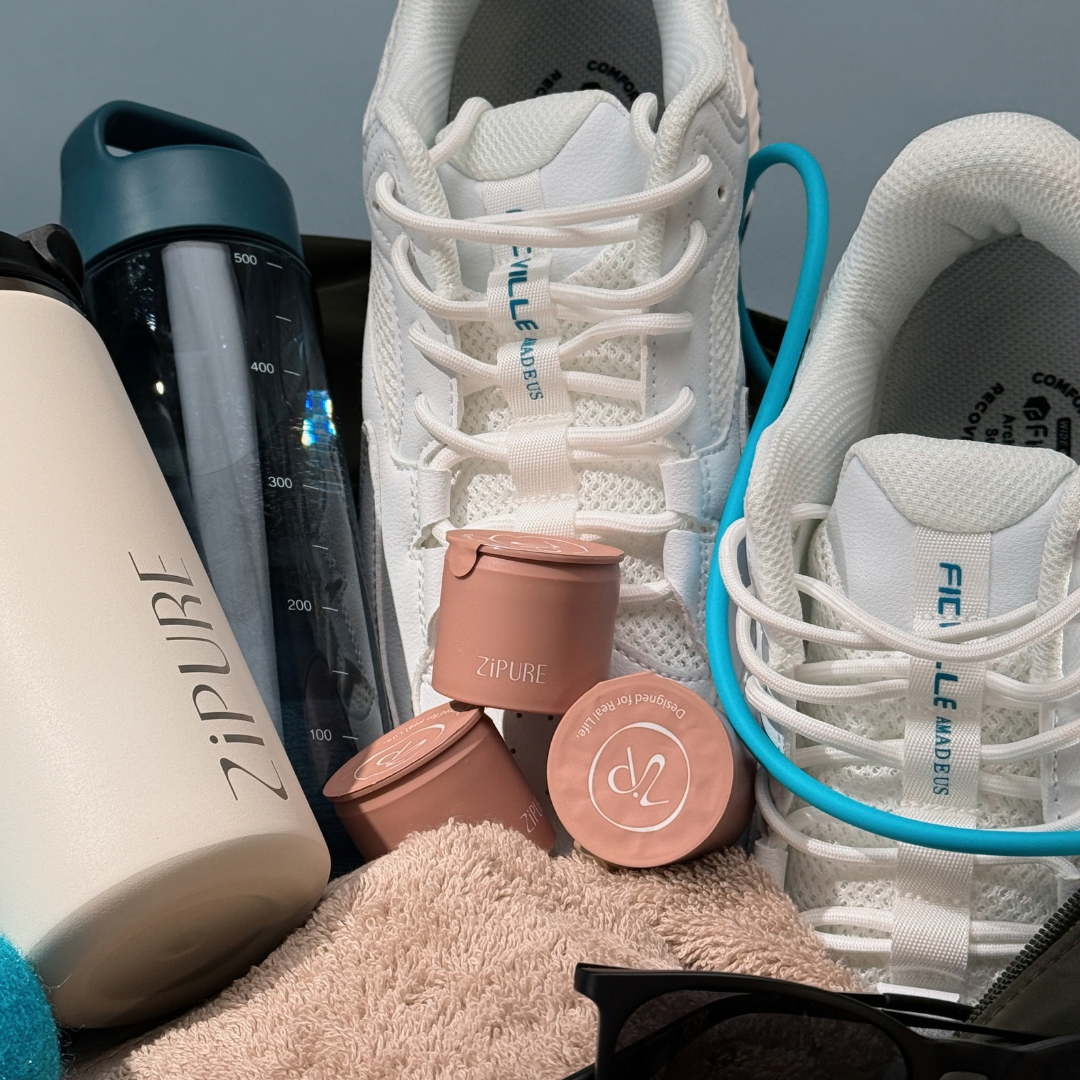 ZIPURE tumbler and coffee pods packed alongside sneakers and a gym towel for on-the-go use